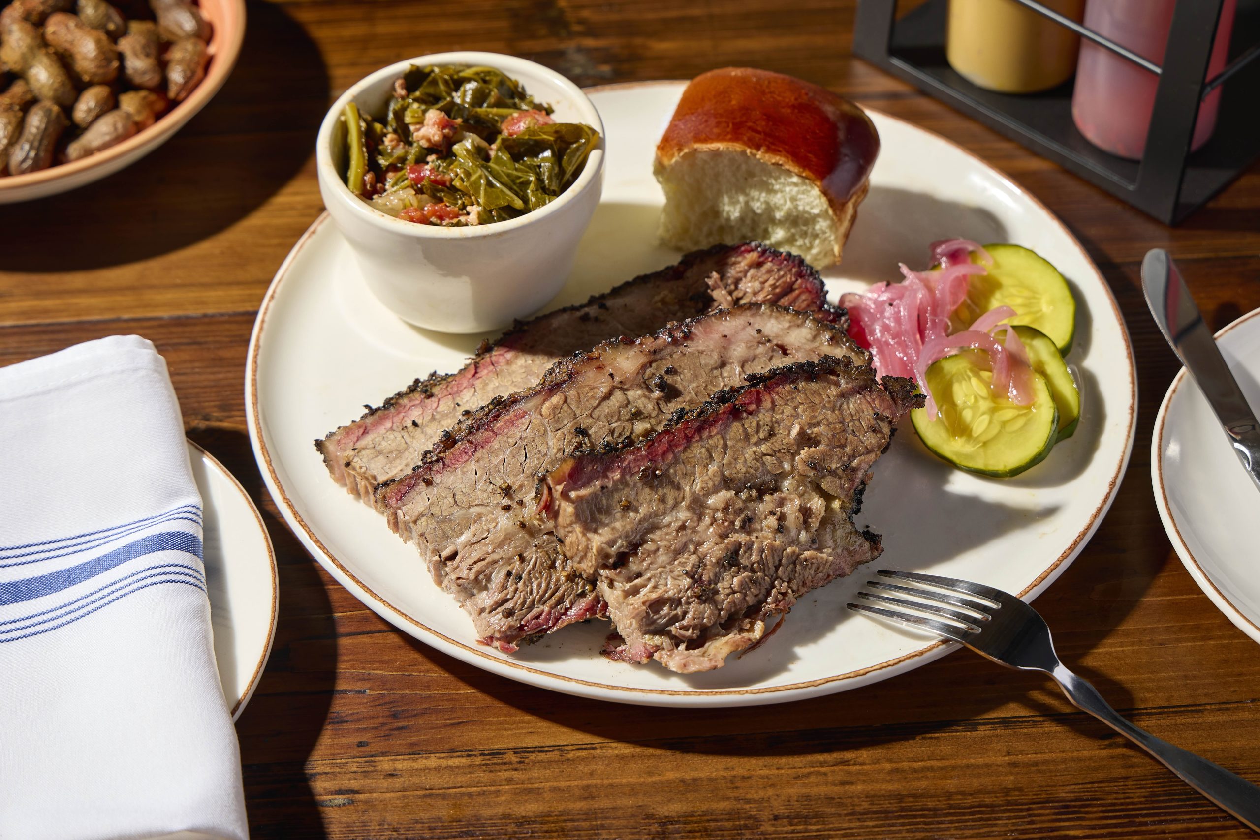 Brisket plate with collard greens, pickles and a roll